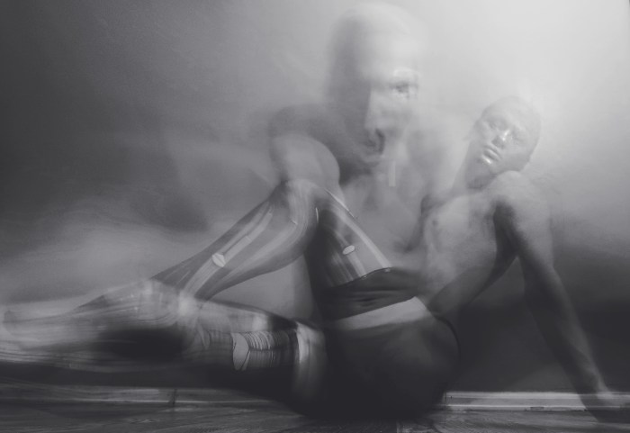 A black and white photo of a person lying on the ground wearing stockings.  A ghost-like image is overlaying the image and looks to be screaming. 