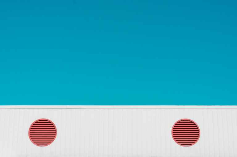 A blue wall with white wainscoting and round, orange air vents.