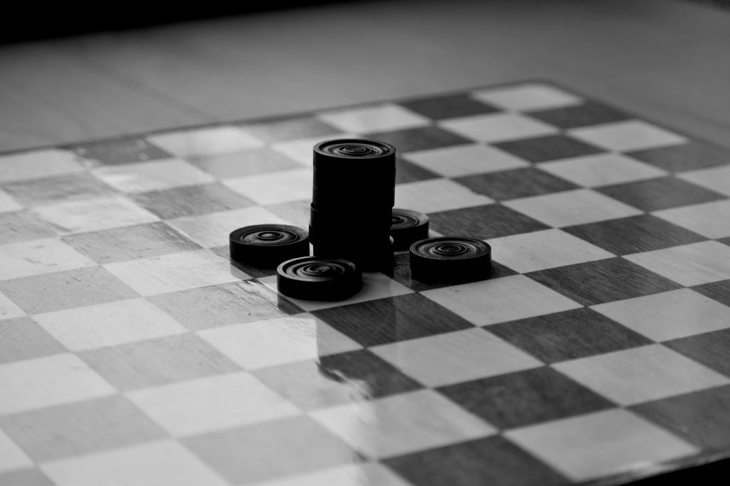 Descriptive image of checkers stacked on a game board.