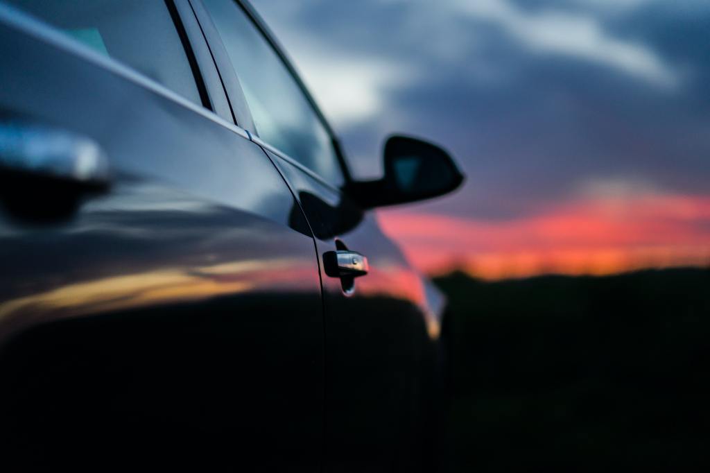 Descriptive image of a side of car during a sunset.