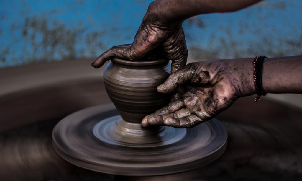 Descriptive image of hands dirty with clay, crafting pottery.