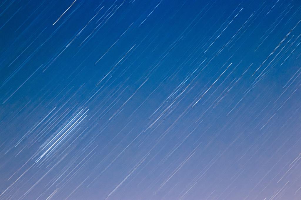 Time-lapse photo of stars moving through the sky; it appears like streaks of light. 
