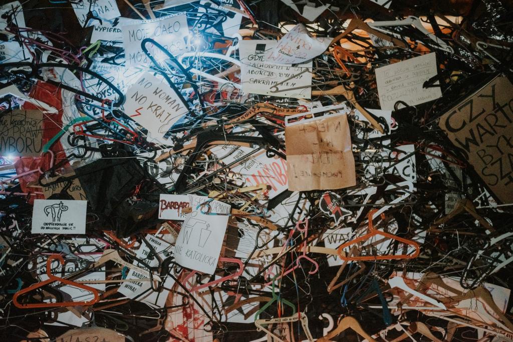 Items for protesting women's rights in a pile together, including plastic clothes hangers and written signs of protest in Polish. 